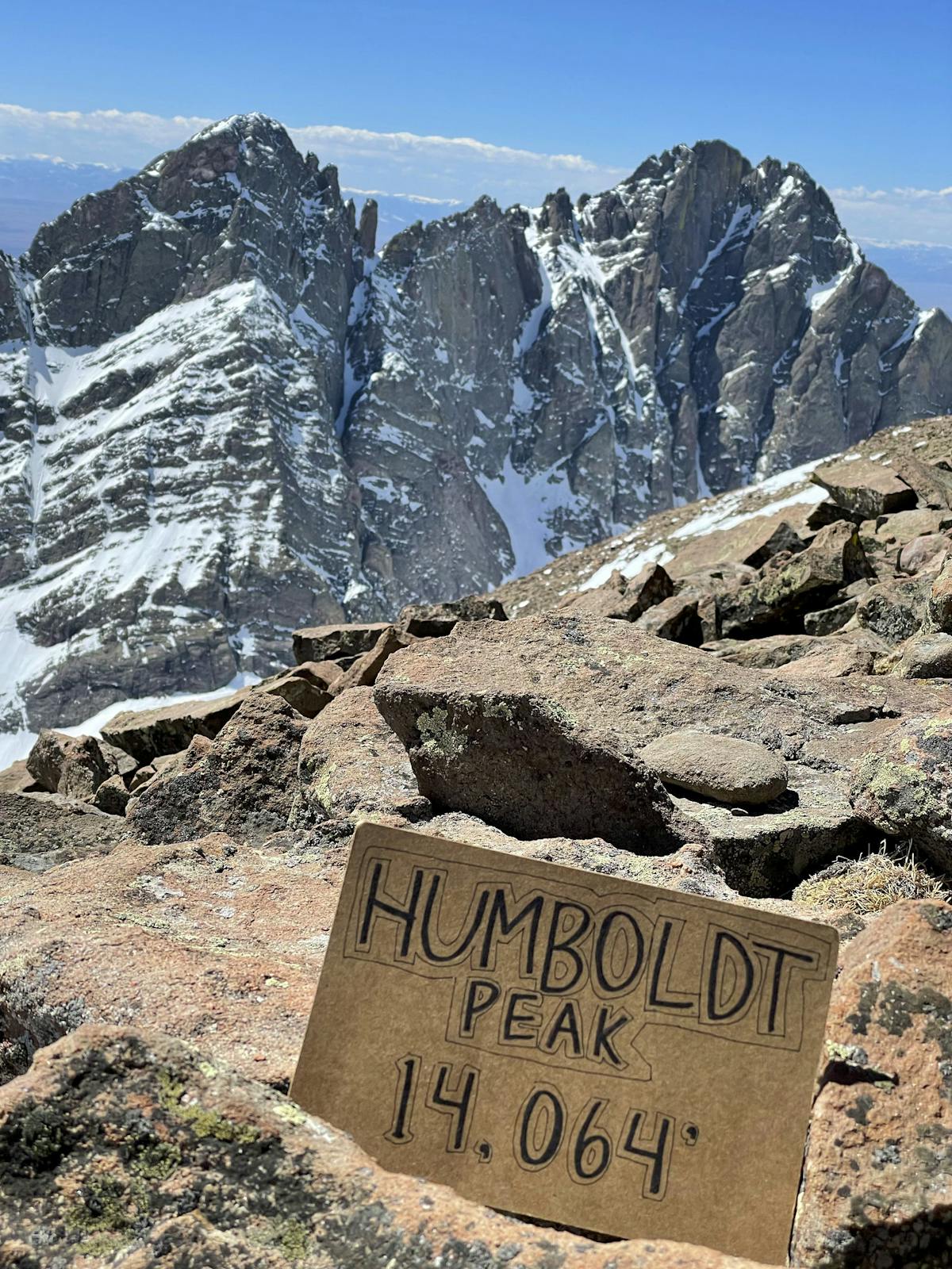 Photo of my summit sign on top of Humboldt Peak. Crestone Peak & Needle are visible in the background.